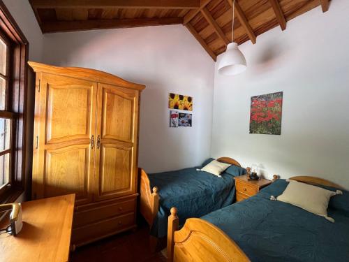 1 dormitorio con 2 camas y armario de madera en Casa Los Calderos, en Mazo