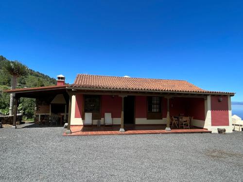 a red and white house with a table and chairs at Casa Los Calderos in Villa de Mazo