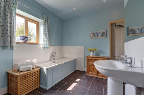 a bathroom with a tub and a sink and a bath tub at Wash House, Rookery Farm in West Beckham