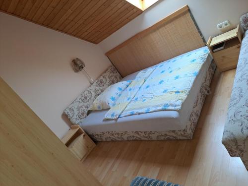 ein kleines Schlafzimmer mit einem Bett und Holzboden in der Unterkunft Alinka Apartmanház in Balatonlelle