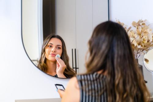 a woman brushing her teeth in front of a mirror at Apartman Panorama in Križevci