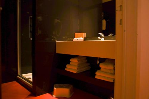 a bathroom with a sink and a pile of towels at Alfa Inn in Blankenberge