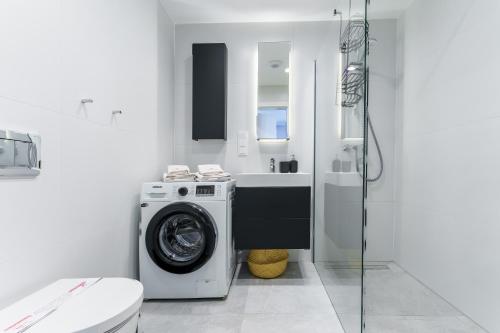 a bathroom with a washing machine and a sink at Apartament Sunrise Shellter - Rogowo in Dźwirzyno