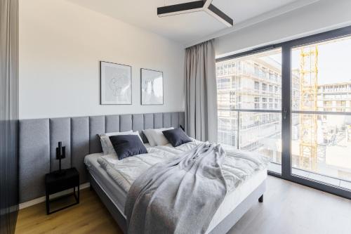 a bedroom with a bed and a large window at Apartament Sunrise Shellter - Rogowo in Dźwirzyno