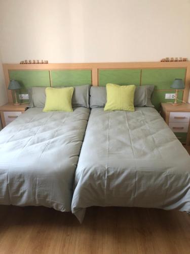 ein großes Bett mit zwei gelben Kissen darauf in der Unterkunft Casa Candelaria in Arguedas