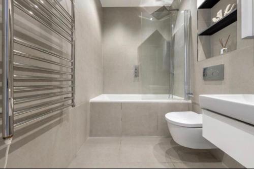 a bathroom with a toilet and a tub and a sink at 1 bed Apartment with parking & GYM in Slough