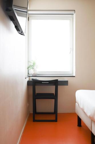 a desk in a room with a window and a bed at Alfa Inn in Blankenberge