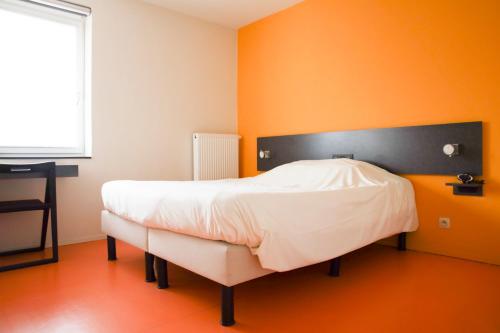 a bed in a room with an orange wall at Alfa Inn in Blankenberge