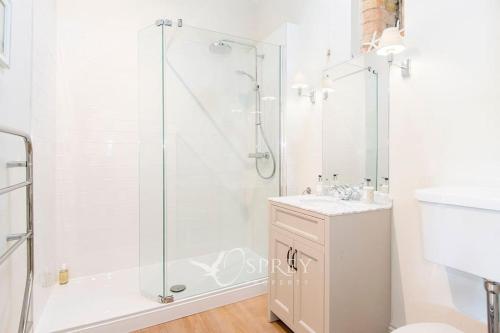 a white bathroom with a shower and a sink at Olive in Oundle