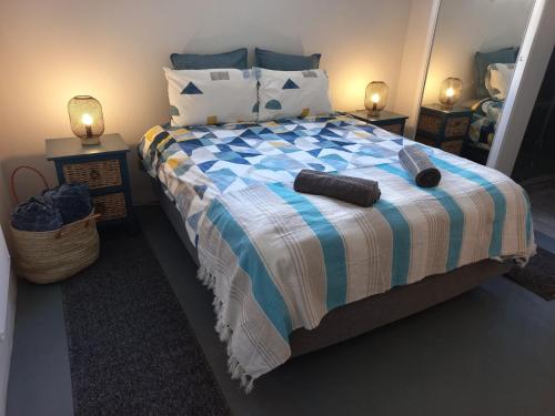a bedroom with a bed with two pillows and two lamps at Lazy Days Apartments - Lambert's Bay in Lambertʼs Bay