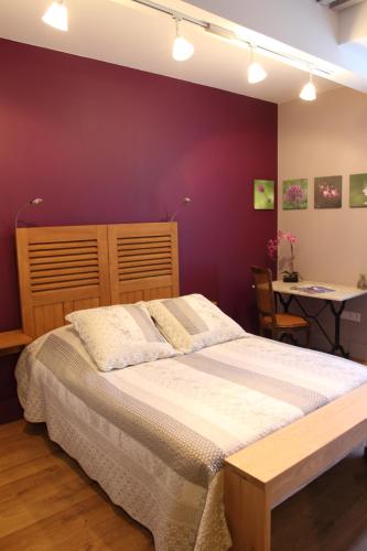 une chambre avec un grand lit et un mur violet dans l'établissement La tour Bocsozel, à La Côte-Saint-André