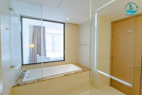 a bathroom with a bath tub and a window at Lumina Villas Cam Ranh, Bai Dai beach luxury resort villas in Cam Ranh