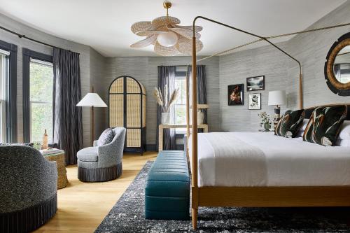 a bedroom with a canopy bed and a chair at The Coco, The Edgartown Collection in Edgartown