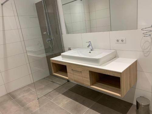 La salle de bains blanche est pourvue d'un lavabo et d'une douche. dans l'établissement Ferienwohnung Siri Zentrum mit Garten, à Sankt Michael im Lungau