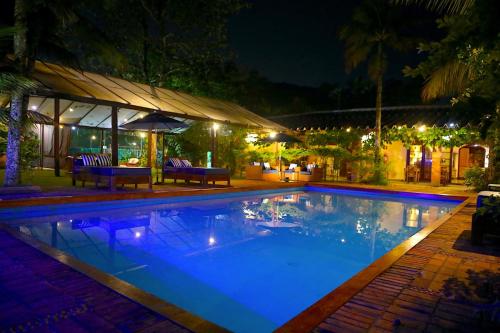 una piscina por la noche con luces encendidas en Canto das Laranjeiras Beach Club Guaiuba, en Guarujá