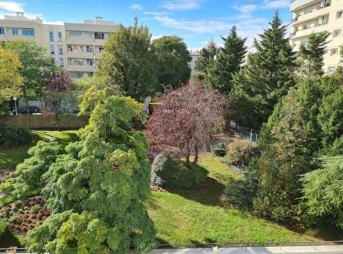 un jardin avec des arbres et des buissons dans une ville dans l'établissement Sunny and renovated flat in secure residence, à La Garenne-Colombes