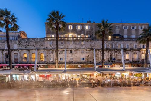 a group of people sitting at tables in front of a building at Guest House Imperial in Split