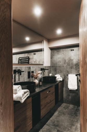 a bathroom with two sinks and a large mirror at Jufenalm BOHO & Wellnesshotel in Maria Alm am Steinernen Meer
