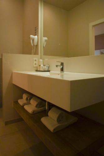 a bathroom with a sink and a mirror and towels at Alfa Inn in Blankenberge