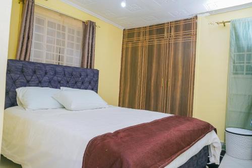 een slaapkamer met een bed met een blauw hoofdeinde en een raam bij Entire Fully furnished Villas in Kisii in Kisii