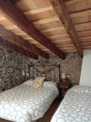 a bedroom with two beds and a stone wall at Apartamento en pleno Montseny Mas Romeu Turisme Rural in Arbúcies