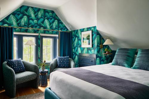 a bedroom with a large bed and two chairs at The Coco, The Edgartown Collection in Edgartown