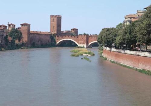 Blick auf einen Fluss mit einer Brücke und Gebäuden in der Unterkunft Arena Maroncelli Rooms in Verona