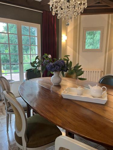 una mesa de comedor con un jarrón de flores. en chambres d'hôtes, La cime des pins en Crévin