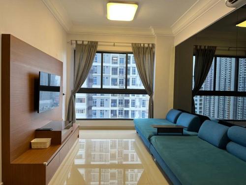 a living room with a blue couch and two windows at Vsummer, Homely Suite by Antlerzone in Johor Bahru