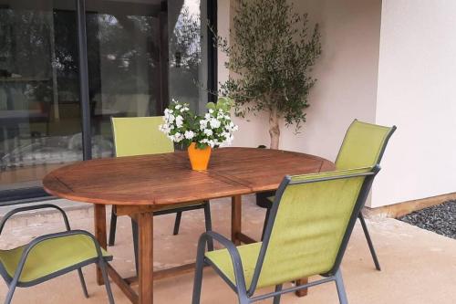 une table en bois avec des chaises et un vase de fleurs dessus dans l'établissement Chez Michael, à Lunan