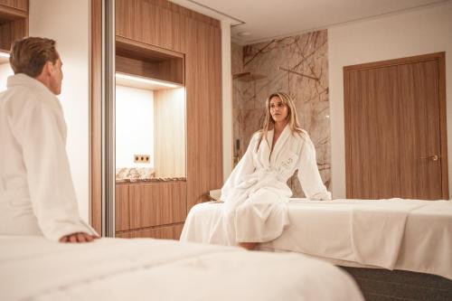 a woman sitting on a bed in front of a mirror at Ermitage de l'Oasis & Spa - Cannes Mandelieu in Mandelieu-la-Napoule