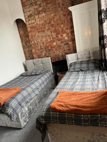 twee bedden in een kamer met een bakstenen muur bij Quigley Buildings - Stylish Entire 2 bed House sleeps 5 Wigan - Private Garden - Free parking - Wifi - Secure garden in Pemberton