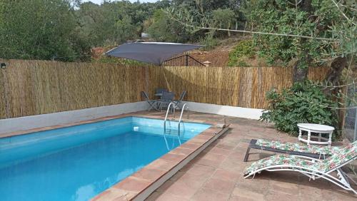 einen Pool mit 2 Stühlen und einem Sonnenschirm in der Unterkunft Casa rural con encanto in Colmenar