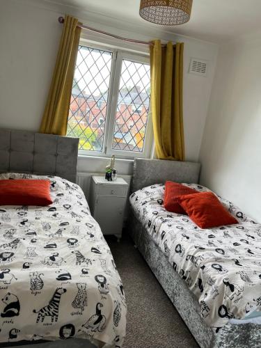 a bedroom with two beds and a window at Treetops - Sleeps 8 entire house private parking close to town centre and stadium in Wigan