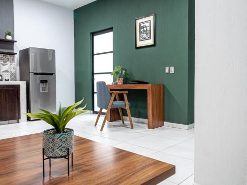a kitchen with green walls and a table and a chair at Depas Mololoa in Tepic