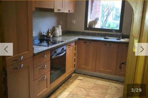 a kitchen with wooden cabinets and a cat looking out the window at palmeraie village 2 in Marrakech