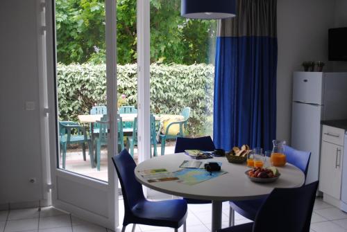 Il dispose d'une terrasse et d'une cuisine avec une table et des chaises blanches. dans l'établissement VVF Golfe du Morbihan Sarzeau Arzon, à Sarzeau
