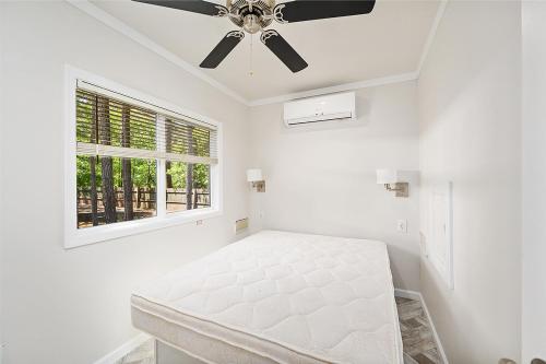 een witte slaapkamer met een bed en een plafondventilator bij Sun Outdoors Chincoteague Bay in Chincoteague