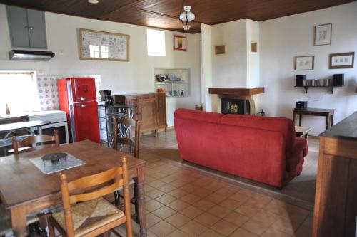 a living room with a red couch and a kitchen at Marilune in Coux-et-Bigaroque