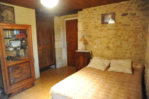 a bedroom with a bed and a stone wall at Marilune in Coux-et-Bigaroque