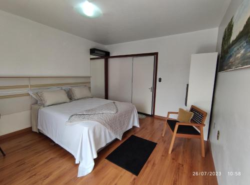 a bedroom with a white bed and a wooden floor at Pousada com vista para o Cristo 4 in Encantado