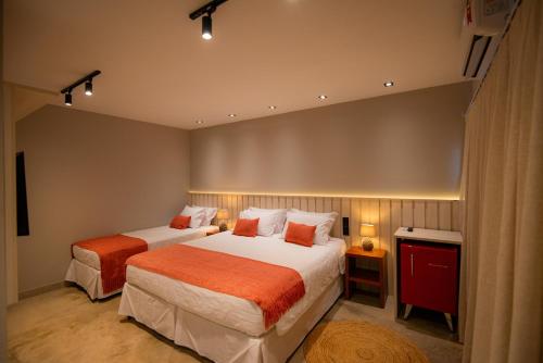 ein Hotelzimmer mit 2 Betten mit orangefarbener Bettwäsche in der Unterkunft Pousada Xica in Fernando de Noronha