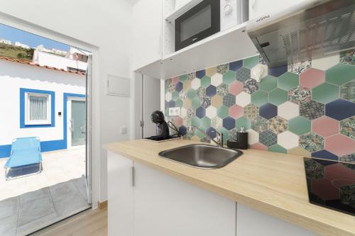 uma cozinha com um lavatório e um micro-ondas em Pátio C'un Casinhas na Nazaré