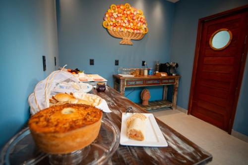 a table with a cake and a plate of bread at Pousada Xica in Fernando de Noronha