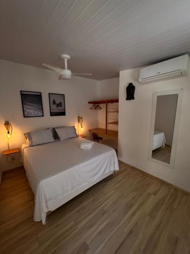 a bedroom with a white bed and a mirror at Bada Hostel & Kite School in Cumbuco