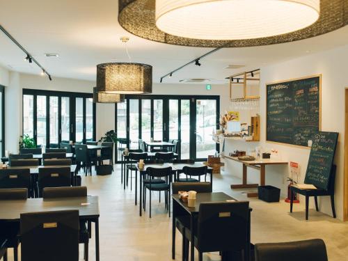 a restaurant with tables and chairs and a chalkboard at Showcase Hotel KASANE in Gotsu
