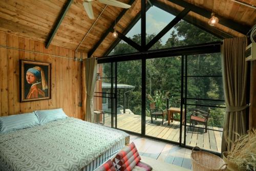 a bedroom with a bed and a large glass window at Wilderness Treehouse in Doi Saket