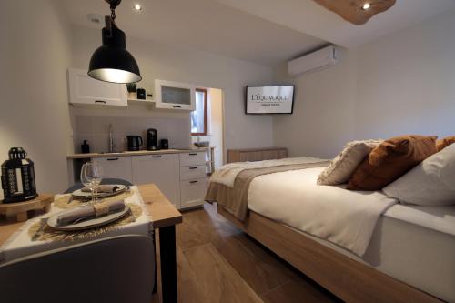 Cet appartement comprend une chambre avec un lit et une table ainsi qu'une cuisine. dans l'établissement Gîte de charme avec jacuzzi et sauna privatifs, à Donzère