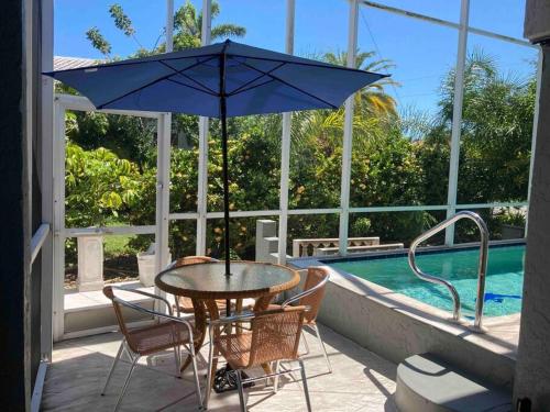 - une table et des chaises avec un parasol sur la terrasse dans l'établissement Stylish & Cheerful Marco Home w/ Awesome Location, à Marco Island