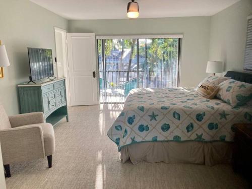 a bedroom with a bed and a chair and a window at Stylish & Cheerful Marco Home w/ Awesome Location in Marco Island